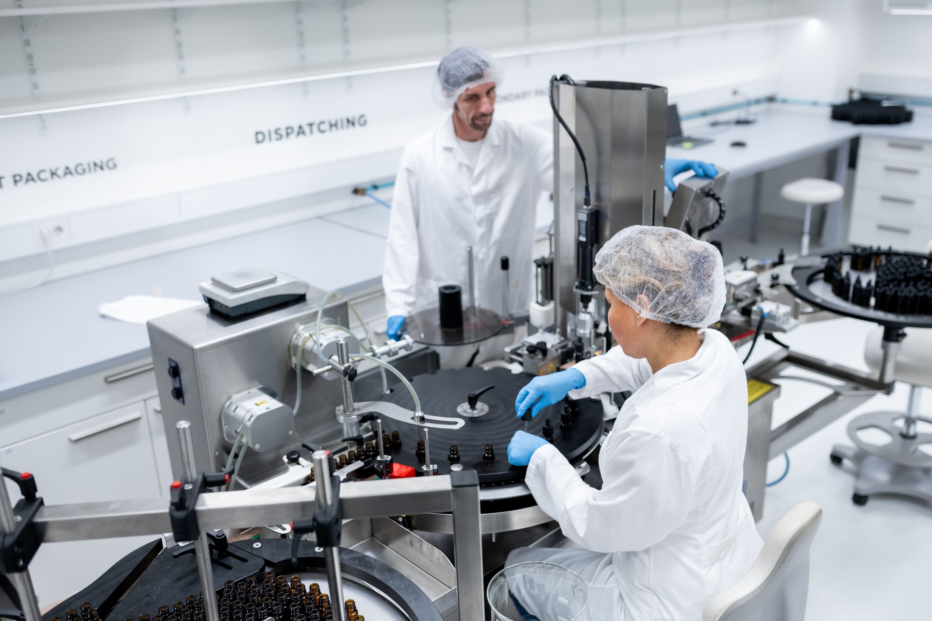 Pharmaceutical workers on the production line for filling and packing bottles.