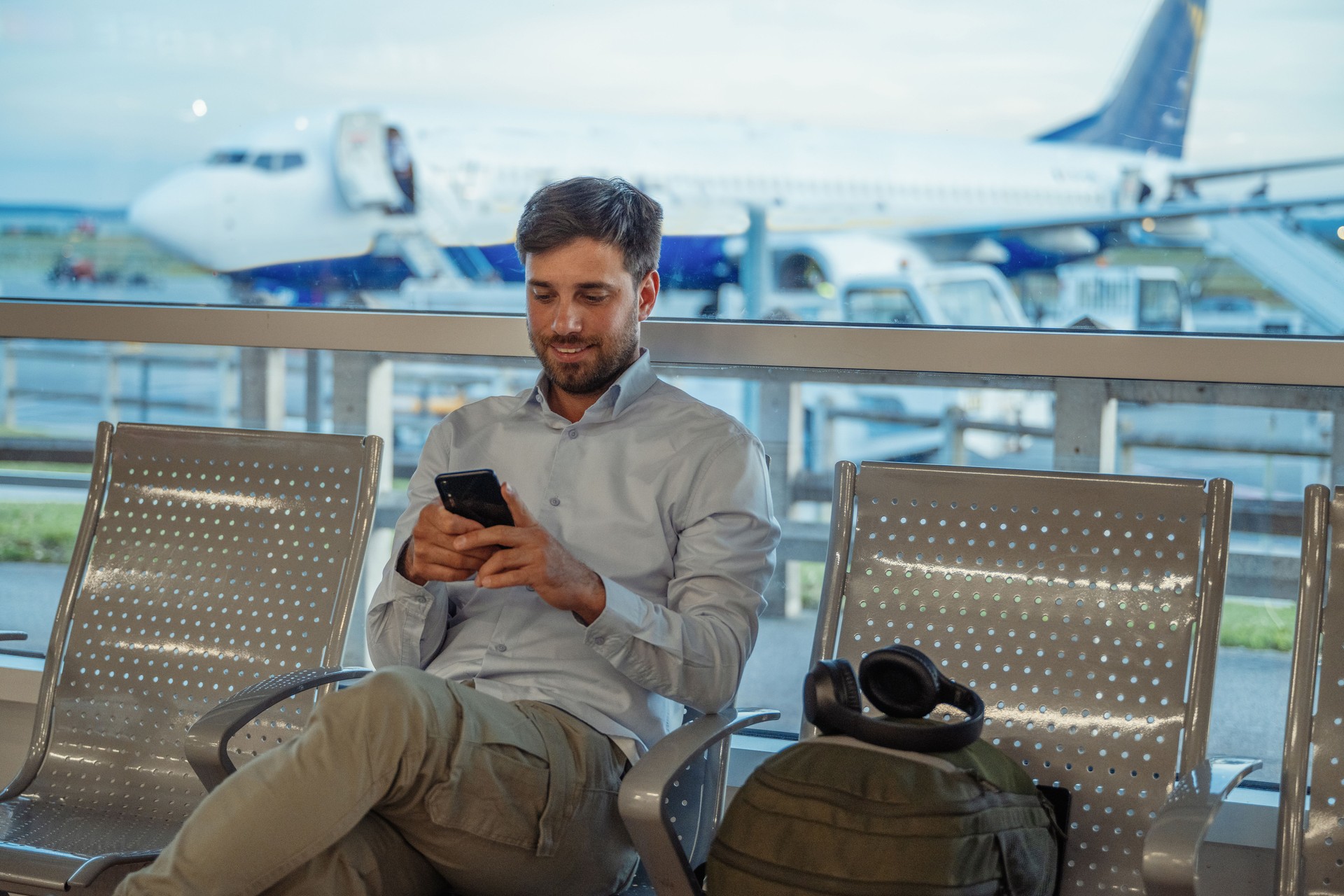 Young businessman at the airport waiting for the flight. Businessman using smart phone